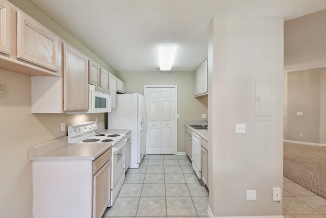 kitchen with white appliances, light tile patterned flooring, a sink, light countertops, and a textured ceiling