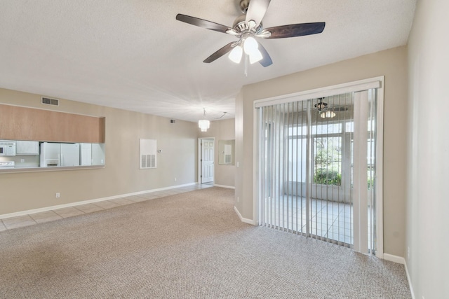 unfurnished room featuring a textured ceiling, carpet, visible vents, and baseboards