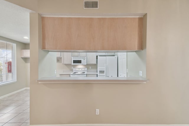 kitchen featuring light tile patterned flooring, visible vents, white appliances, and light countertops