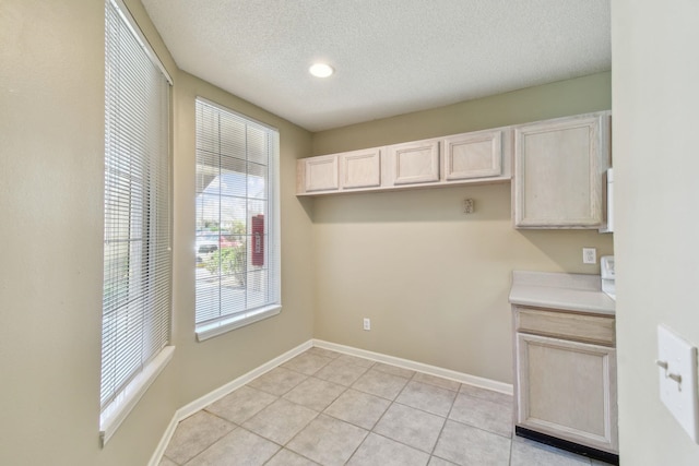 washroom featuring light tile patterned flooring, baseboards, and a textured ceiling