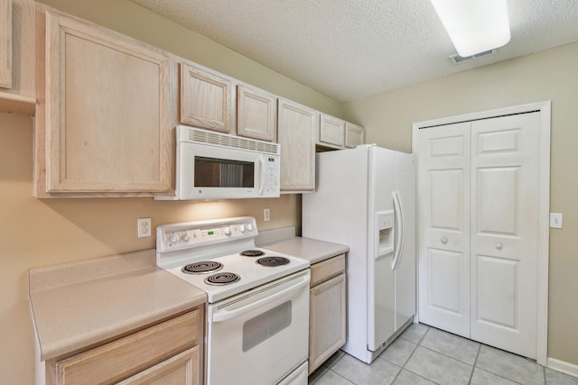 kitchen with white appliances, light brown cabinets, visible vents, and light countertops