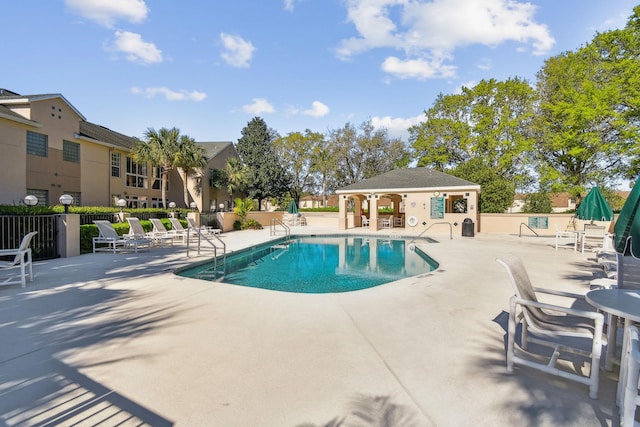 community pool with a patio area and fence