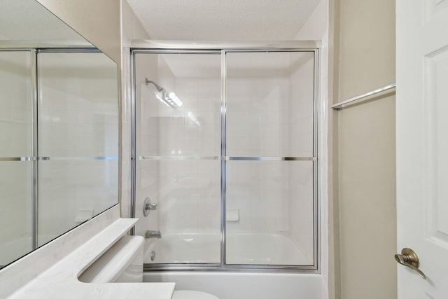 full bathroom featuring vanity, toilet, bath / shower combo with glass door, and a textured ceiling