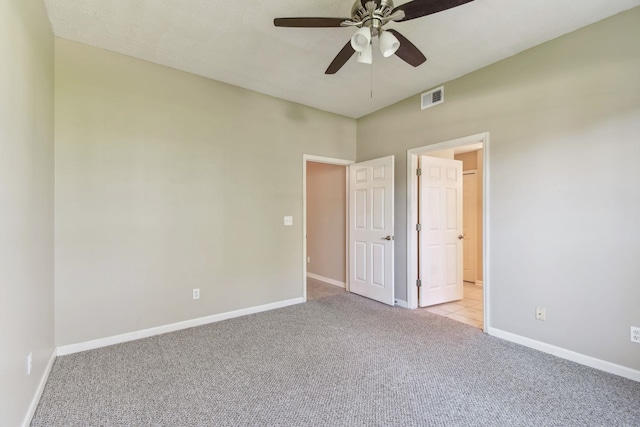 unfurnished bedroom featuring visible vents, baseboards, light colored carpet, and a ceiling fan