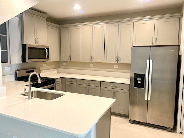 kitchen featuring sink, gray cabinets, kitchen peninsula, and appliances with stainless steel finishes