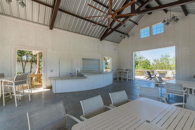 dining space with high vaulted ceiling, beamed ceiling, and wood walls