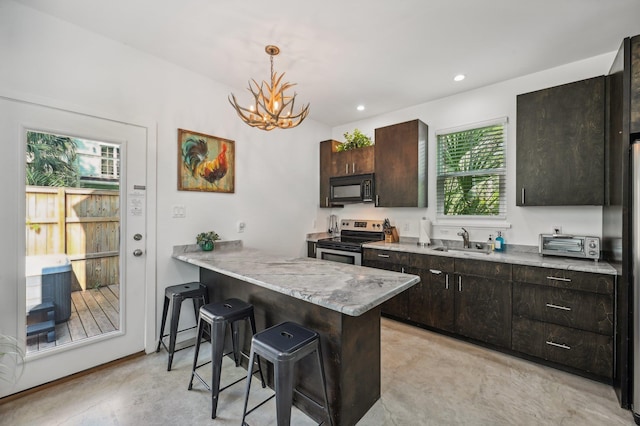 kitchen featuring black appliances, a sink, a kitchen breakfast bar, concrete floors, and a peninsula