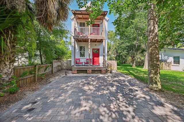 view of front of property featuring a balcony, a front lawn, and fence