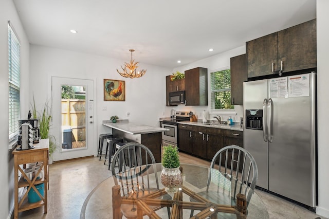 kitchen with stainless steel appliances, hanging light fixtures, sink, and dark brown cabinets