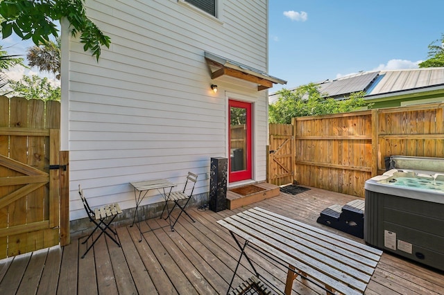 deck with a gate, fence, and a hot tub