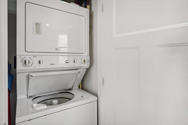 clothes washing area with stacked washing maching and dryer