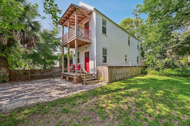 rear view of house featuring a yard, a patio, a balcony, and fence