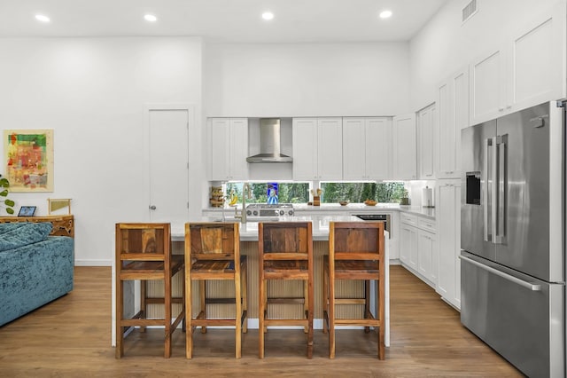 2470 Oleander St, Saint Augustine, FL 32080 - kitchen with high quality fridge, wall chimney exhaust hood, a high ceiling, light countertops, and white cabinets
