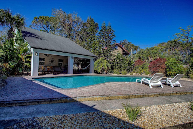 view of swimming pool featuring a patio area, an outbuilding, and ceiling fan