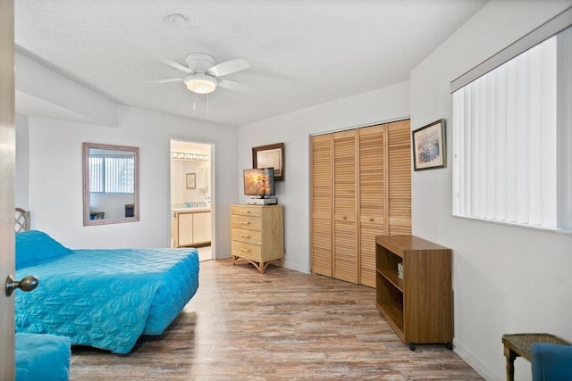 bedroom featuring a textured ceiling, ceiling fan, hardwood / wood-style flooring, connected bathroom, and a closet