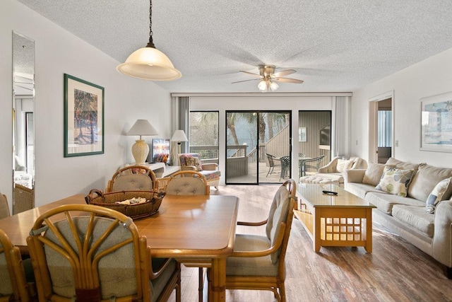 dining space featuring wood-type flooring, a textured ceiling, and ceiling fan