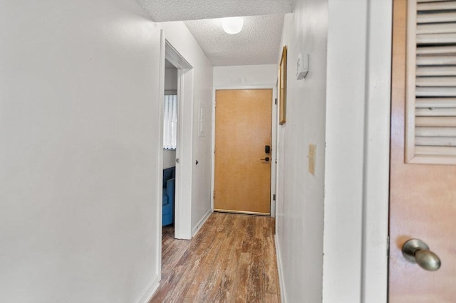 hallway with wood-type flooring and a textured ceiling