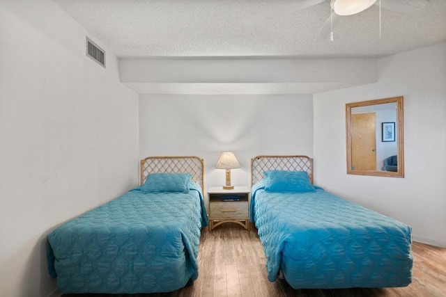 bedroom with ceiling fan, hardwood / wood-style floors, and a textured ceiling