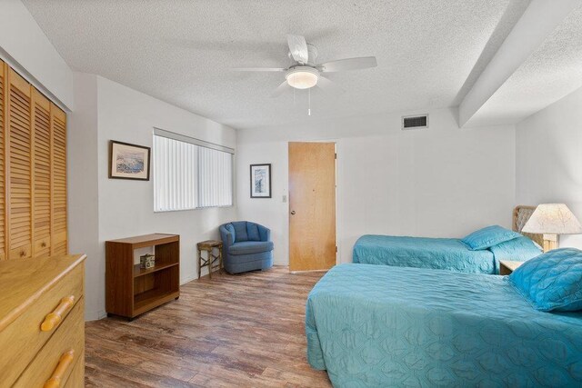 bedroom featuring a textured ceiling, a closet, ceiling fan, and dark wood-type flooring