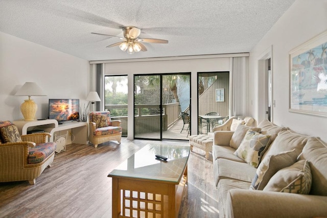 living room with ceiling fan, light wood-type flooring, and a textured ceiling