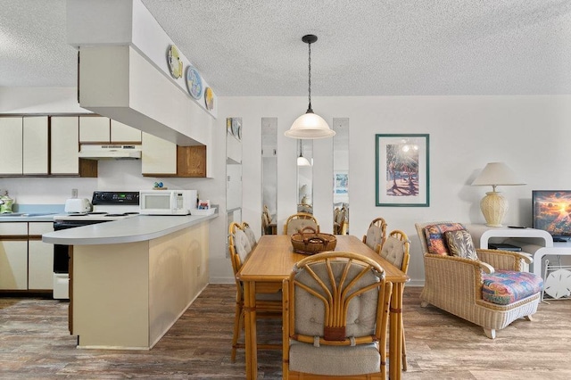 kitchen featuring hardwood / wood-style floors, white appliances, kitchen peninsula, and a textured ceiling