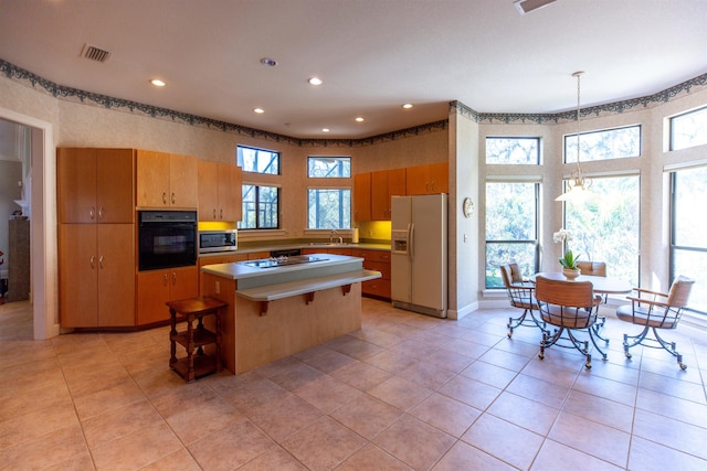 kitchen featuring a healthy amount of sunlight, a kitchen island, decorative light fixtures, and black appliances