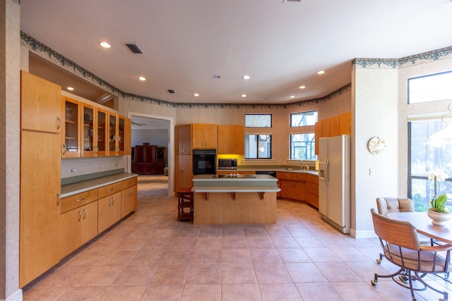 kitchen featuring a healthy amount of sunlight, a breakfast bar, a kitchen island, and black appliances