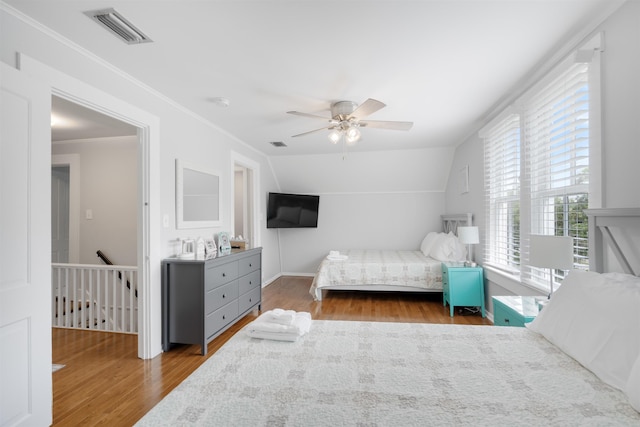 bedroom with ceiling fan, crown molding, dark wood-type flooring, and vaulted ceiling