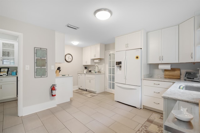 kitchen with white cabinetry, sink, light tile patterned floors, and white appliances