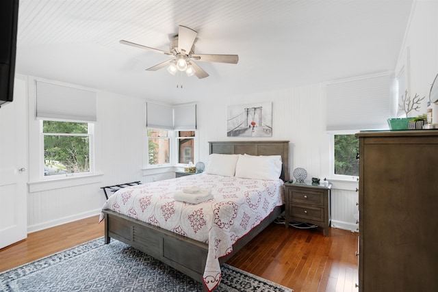 bedroom with multiple windows, ceiling fan, and dark hardwood / wood-style flooring