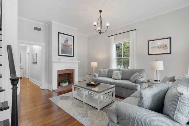 living room with a fireplace, dark hardwood / wood-style floors, an inviting chandelier, and crown molding