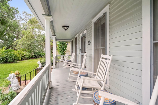 wooden deck with a porch and a lawn