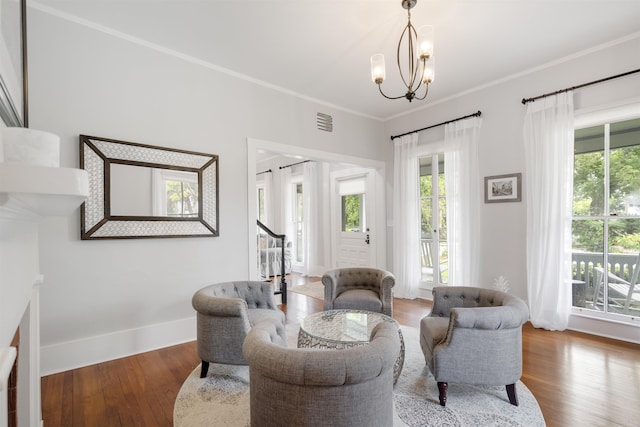 sitting room with hardwood / wood-style flooring, ornamental molding, a wealth of natural light, and an inviting chandelier