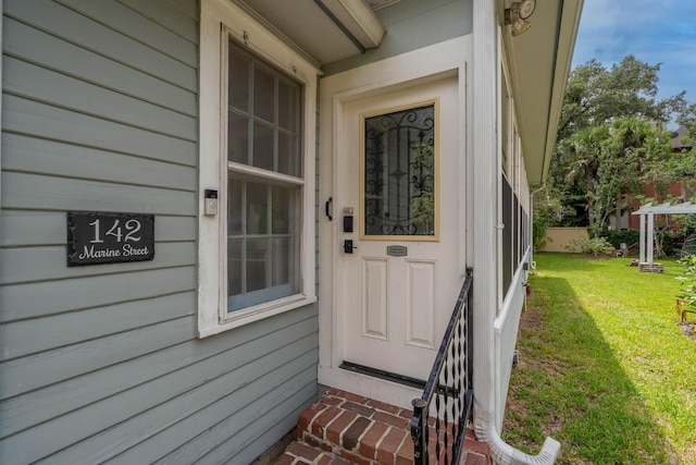 view of exterior entry featuring a lawn