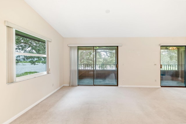 carpeted empty room featuring plenty of natural light and vaulted ceiling