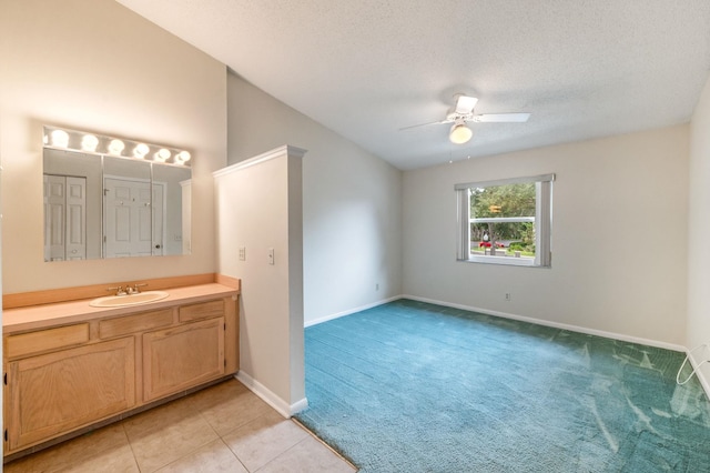 bathroom with ceiling fan, tile patterned flooring, vanity, and a textured ceiling