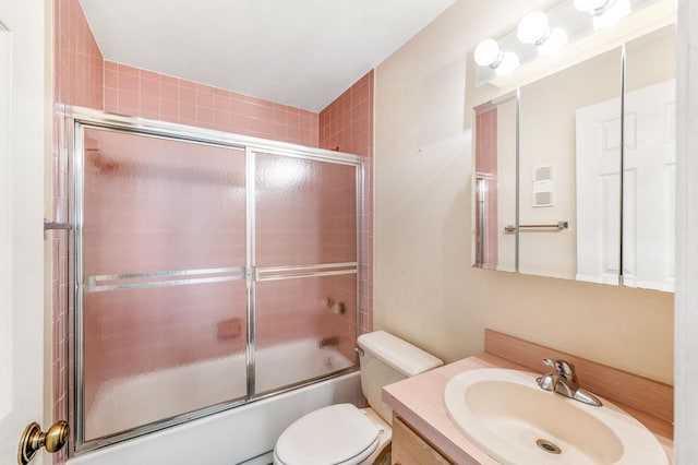 full bathroom featuring vanity, toilet, and shower / bath combination with glass door