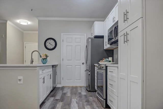 kitchen with sink, crown molding, light hardwood / wood-style floors, white cabinets, and appliances with stainless steel finishes