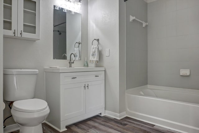 full bathroom featuring vanity, hardwood / wood-style floors, tiled shower / bath combo, and toilet