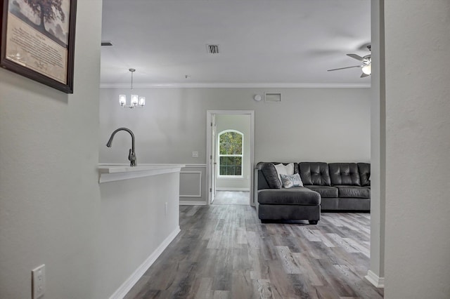 living room featuring sink, hardwood / wood-style floors, ceiling fan with notable chandelier, and ornamental molding