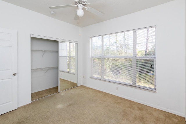 unfurnished bedroom featuring ceiling fan, multiple windows, a closet, and light carpet