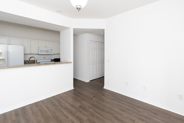 kitchen with white cabinets, dark hardwood / wood-style flooring, sink, and white appliances