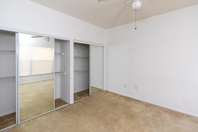 unfurnished bedroom with ceiling fan, light colored carpet, and multiple closets