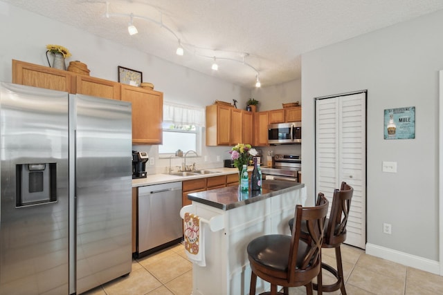 133 Pomar St, Saint Augustine, FL 32084 - kitchen with stainless steel appliances, light tile patterned floors, a center island, a breakfast bar area, and a textured ceiling