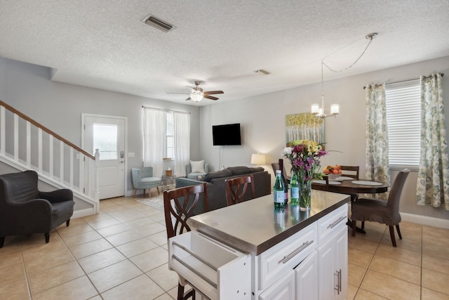 133 Pomar St, Saint Augustine, FL 32084 - kitchen with open floor plan, light tile patterned floors, a chandelier, a textured ceiling, and white cabinetry