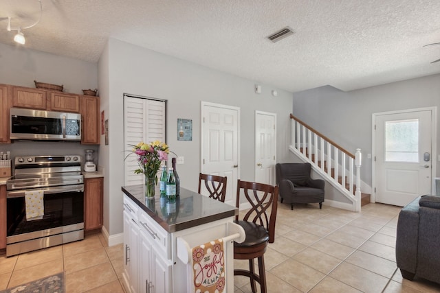 133 Pomar St, Saint Augustine, FL 32084 - kitchen featuring stainless steel appliances, open floor plan, a textured ceiling, a kitchen breakfast bar, and light tile patterned flooring
