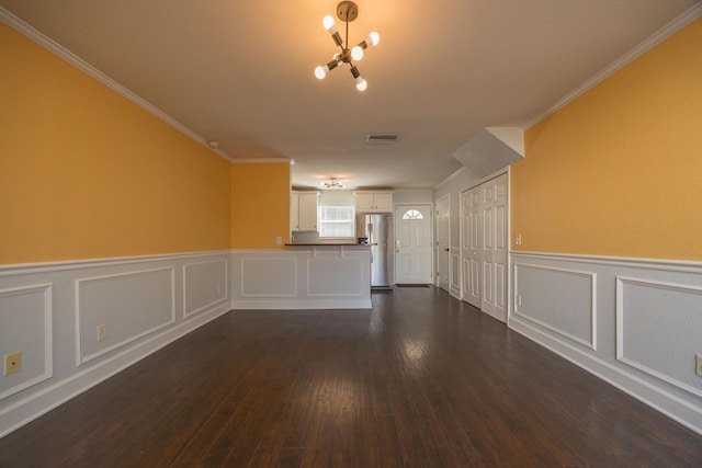 empty room featuring dark hardwood / wood-style floors, ornamental molding, and an inviting chandelier