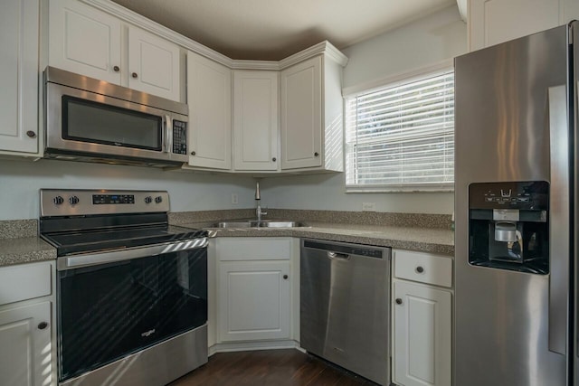 kitchen featuring white cabinets, appliances with stainless steel finishes, dark wood-type flooring, and sink