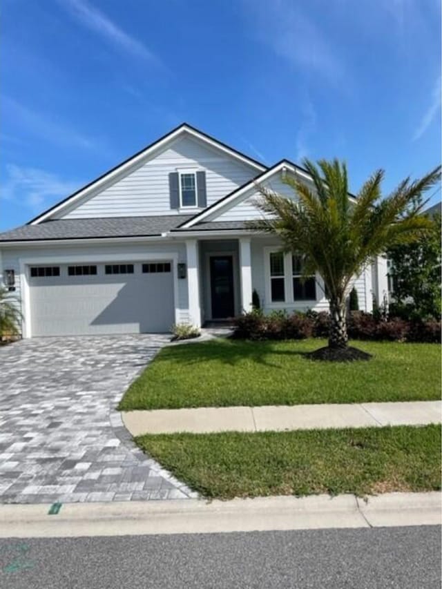 view of front facade featuring a garage, a front lawn, and decorative driveway