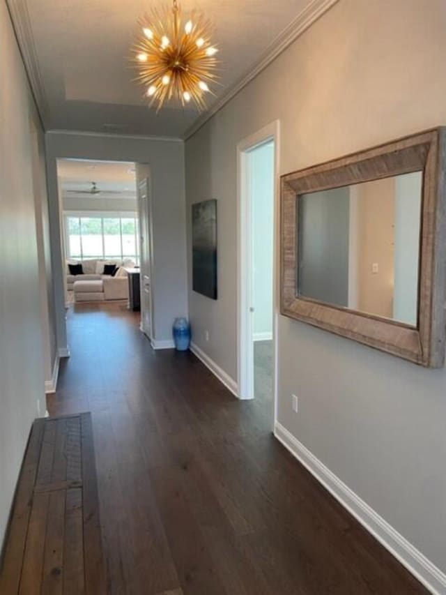 hallway with a chandelier, baseboards, dark wood finished floors, and crown molding